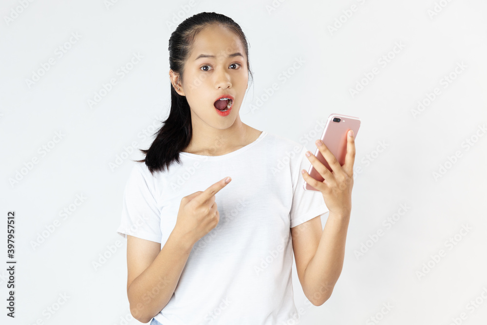 Excited young pretty Asian woman in white shirt pointing finger and using smartphone on the white background
Excited young pretty Asian woman in white shirt pointing finger and using smartphone on the white background