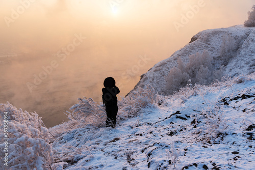 The girl takes photos at sunset. View of a beautiful river  a lake without ice. Beautiful  winter landscape.