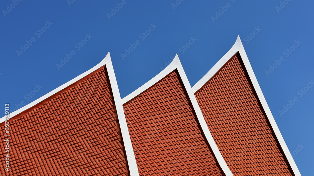 Part of the building's roof in futuristic style. Modern roof and red tiled roof on a blue sky background. Selective focus Part of the building's roof in futuristic style. Modern roof and red tiled roof on a blue sky background. Selective focus