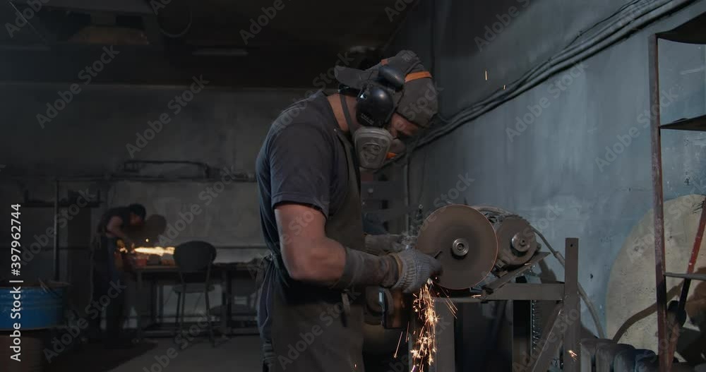 The general plan of a carpentry workshop where two brutal workers work at grinding machines, they process metal blanks, forming many sparks. High quality 4k footage