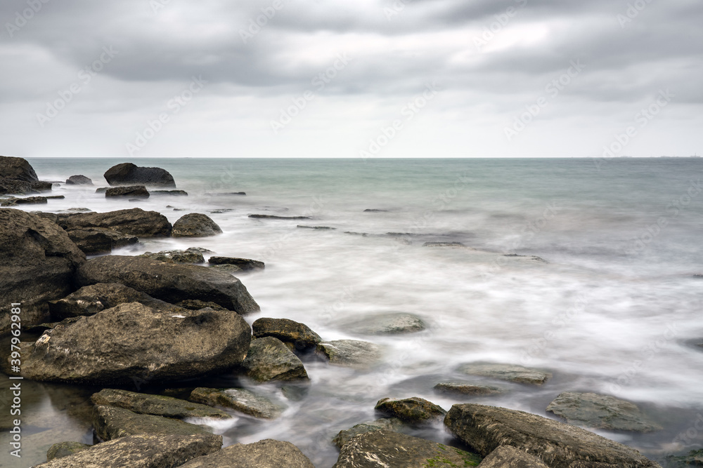Long exposure, rocky sea beach at cloudy weather Long exposure, rocky sea beach at cloudy weather