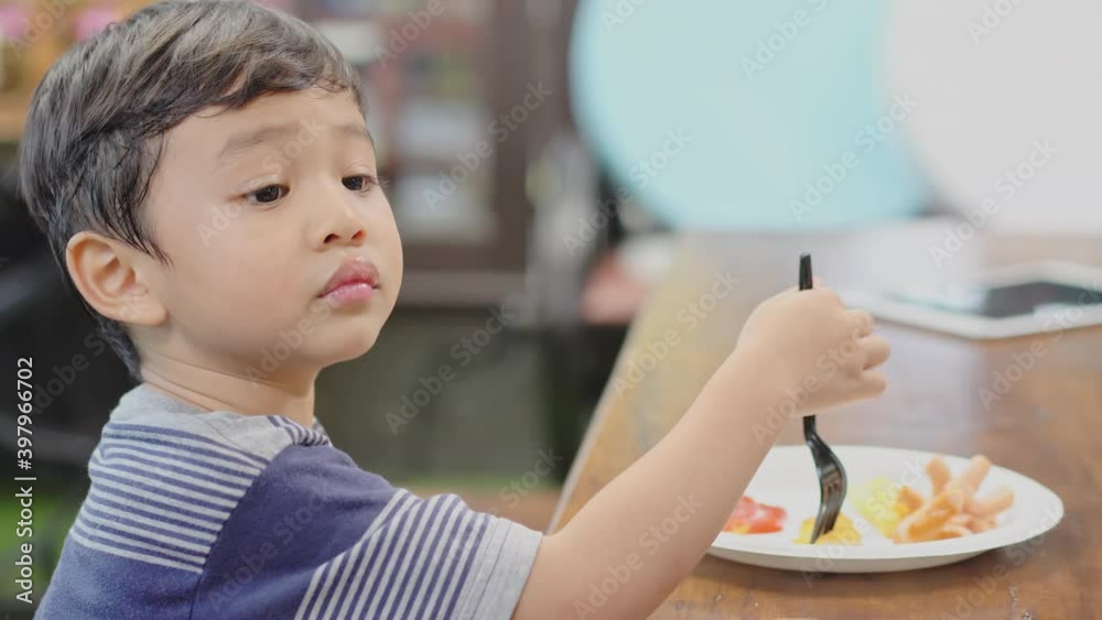 Handheld shot: Asian boy enjoy eating snack at cafe restaurant Handheld shot: Asian boy enjoy eating snack at cafe restaurant