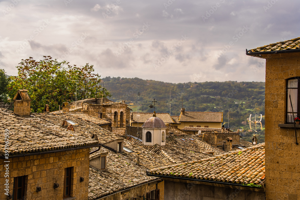 2015-09-01 ROOF TOPS IN THE TUSCANY REGION OF ITALY WITH A BLURRED BACKGROUND OF TREES AND CLOUDS