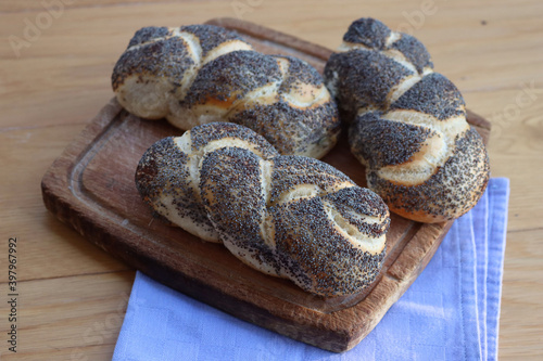 Three braided breads with poppy seeds on wooden table  photo