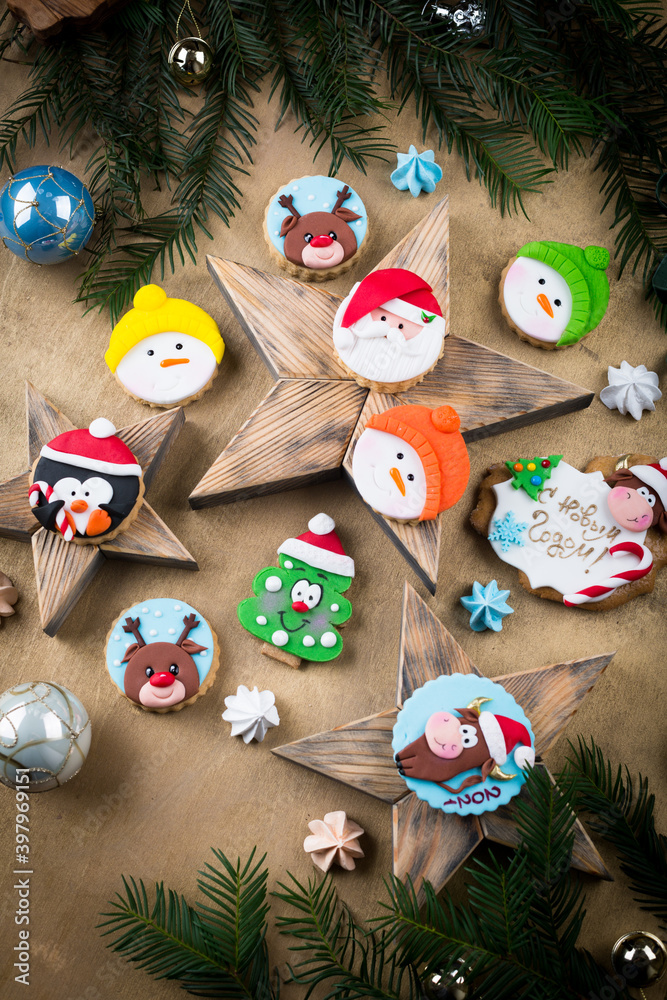 Christmas cookies and cupcakes decorated with icing and marzipan. Various colorful new year pastry gift in Christmas set up, reindeer, Santa on wooden star shape background, copy space