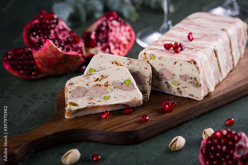 Obraz na plátně Sliced delicious terrine on wooden cutting board with pomegranate seeds on green background