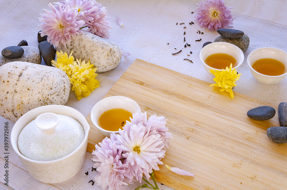 small Chinese white tea cups with black tea on a bamboo board, beautiful white porcelain gaiwan zhong, flowers and stones Typical chinese teaware small Chinese white tea cups with black tea on a bamboo board, beautiful white porcelain gaiwan zhong, flowers and stones Typical chinese teaware