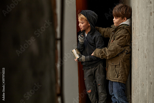 two friendly orphans in city streets, stand looking at strangers in street walking, begging money