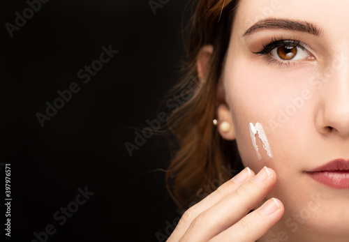 Studio shot of a young woman aplying face cream photo