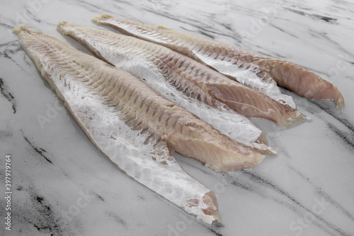 Gastronomy. Fresh seafood ingredients for cooking. Closeup view of raw hake filets on the kitchen table. 