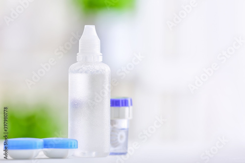 Containers with contact lenses and solution on blurred background