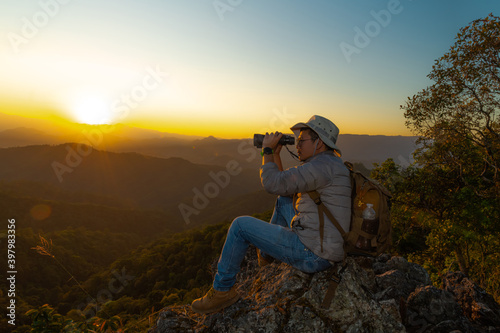 Adventurous man with binoculars standing in the forest