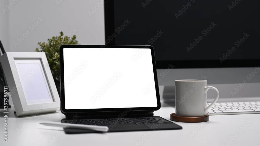 Fototapeta premium Modern work place with blank screen computer tablet, coffee cup and frame on white table.