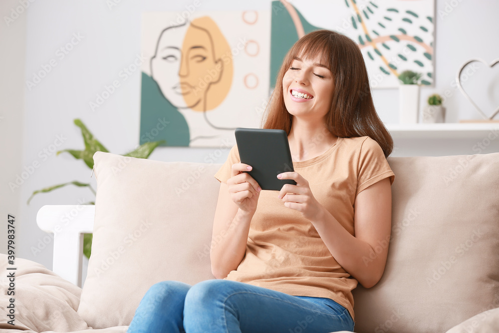 Young woman reading e-book at home