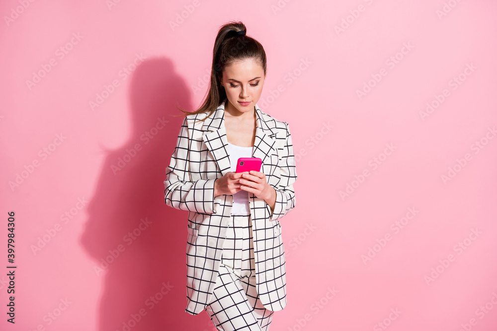 Photo portrait of woman holding phone in two hands isolated on pastel pink colored background Photo portrait of woman holding phone in two hands isolated on pastel pink colored background