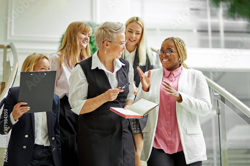 Fotografía group of african and caucasian business women happily talking about something,we