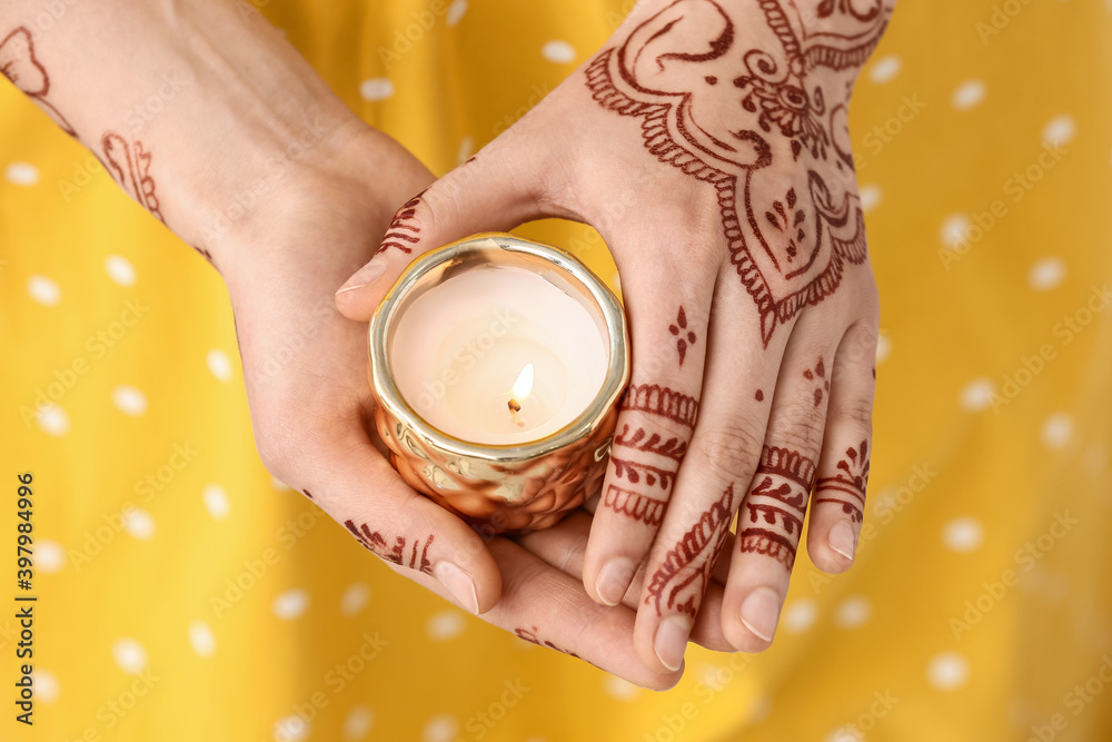 Beautiful woman with henna tattoo on her hands and candle, closeup Beautiful woman with henna tattoo on her hands and candle, closeup