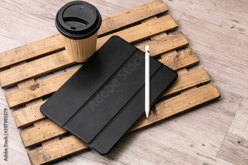 紙コップの飲み物と黒いタブレット端末が木製の机に置いてある　tablet cofee pen photo