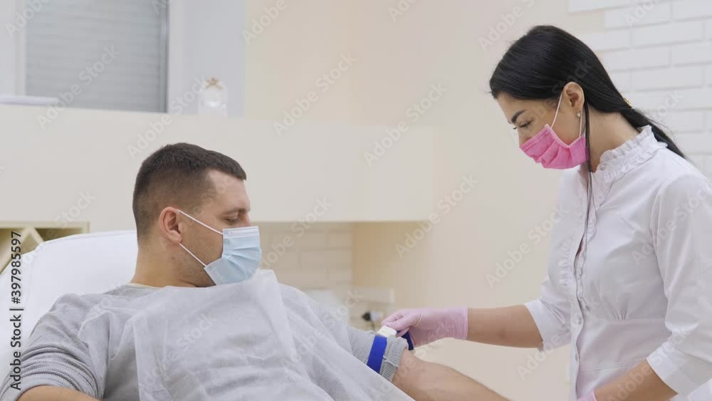Young female doctor injecting male patient with syringe to collect blood sample in clinic Young female doctor injecting male patient with syringe to collect blood sample in clinic