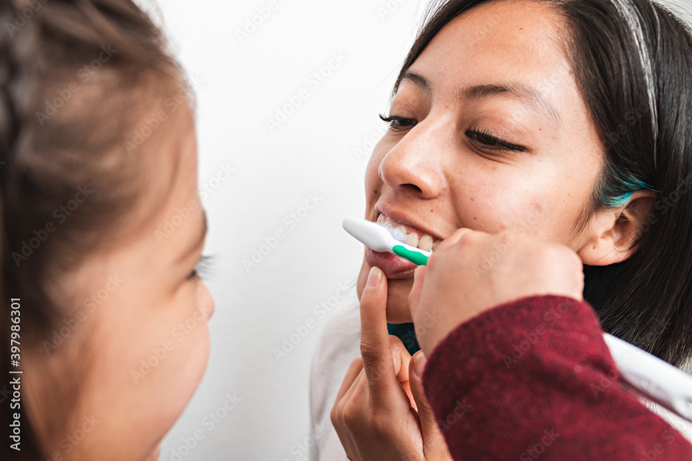 A girl brushing the teeth of a woman A girl brushing the teeth of a woman