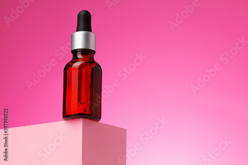 Beauty oil bottle with pipette against pink background