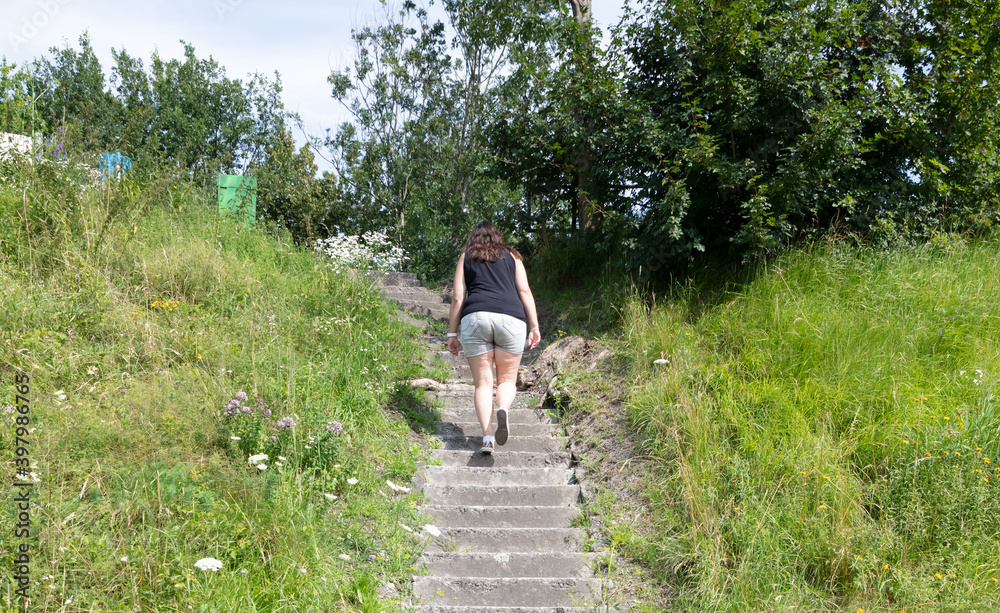 Woman climbing old concrete overgrown with grass stairs