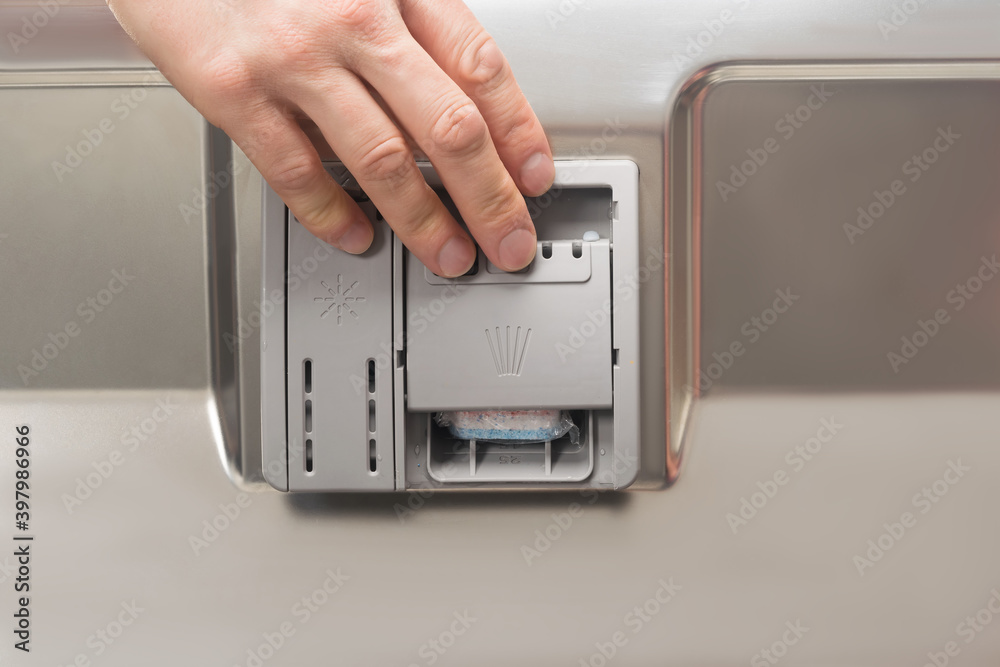 hand opens the compartment for the detergent in the door of the dishwasher, close-up hand opens the compartment for the detergent in the door of the dishwasher, close-up
