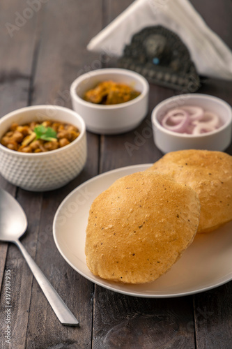 Spicy chick peas curry or Chana Masala or choley with fried puri garnished with sliced onion and green coriander leaf