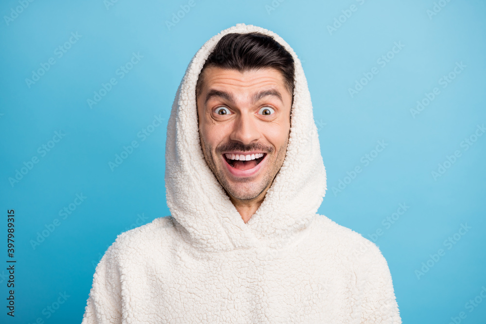Photo portrait of amazed man wearing wool hood isolated on pastel blue colored background Photo portrait of amazed man wearing wool hood isolated on pastel blue colored background
