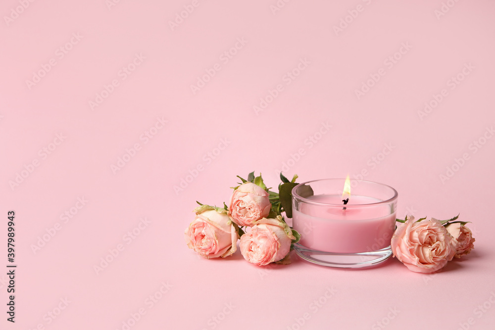 Scented candle and roses on pink background