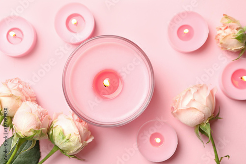 Scented candles and roses on pink background