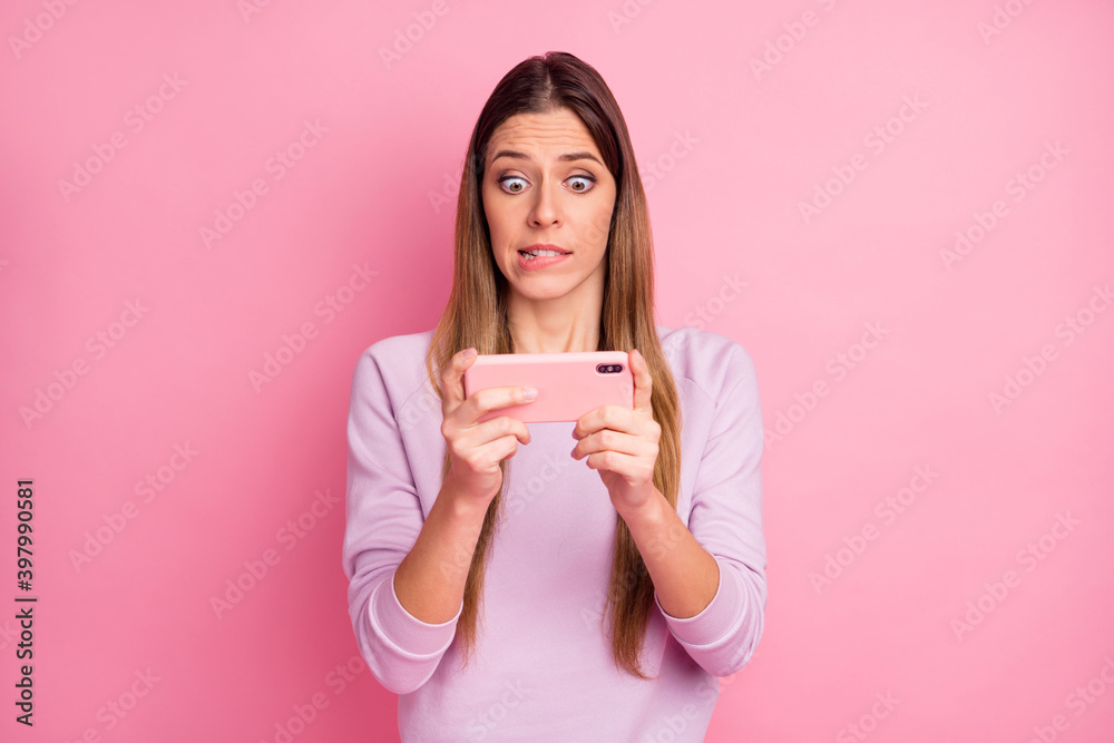 Portrait of pretty worried straight-haired girl using cell playing web app network biting lip isolated over pink pastel color background Portrait of pretty worried straight-haired girl using cell playing web app network biting lip isolated over pink pastel color background