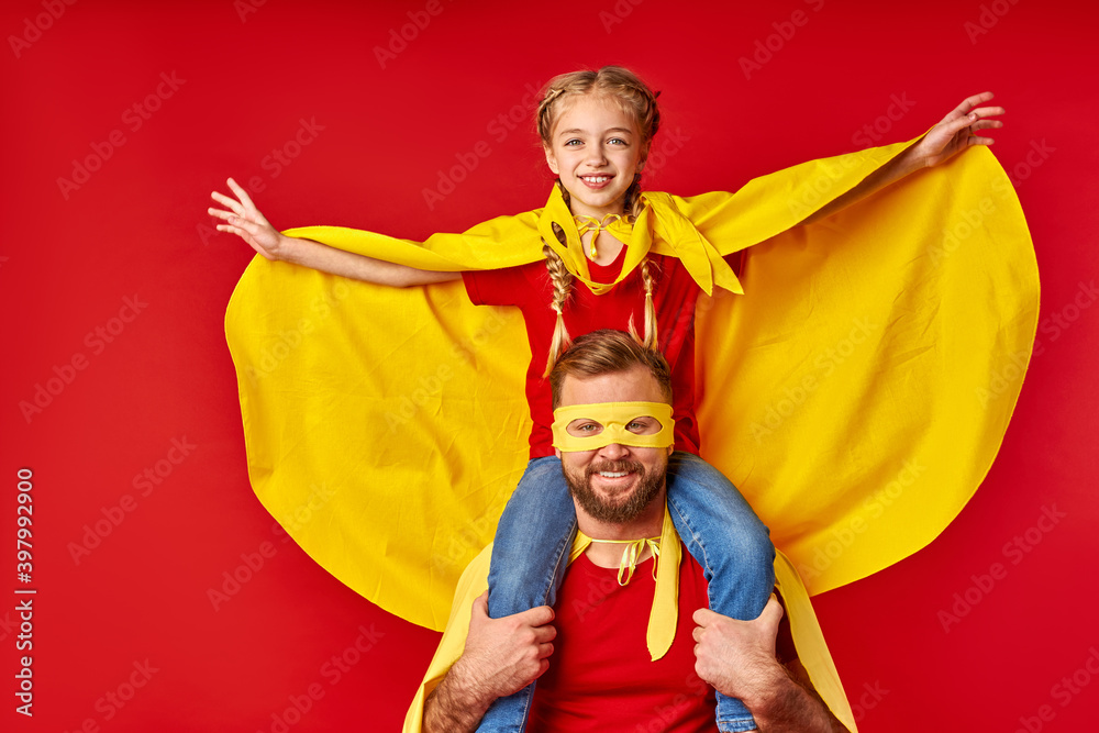 kid girl on dad's neck, play superhero game, imitate flight, smile. happy parent and daughter in supehero costumes posing at camera, smile