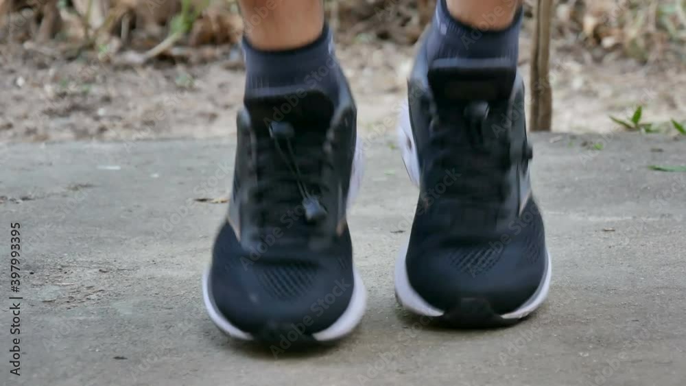 athletic feet with black sneakers jogging on concrete floor at home. Workout at home concept.