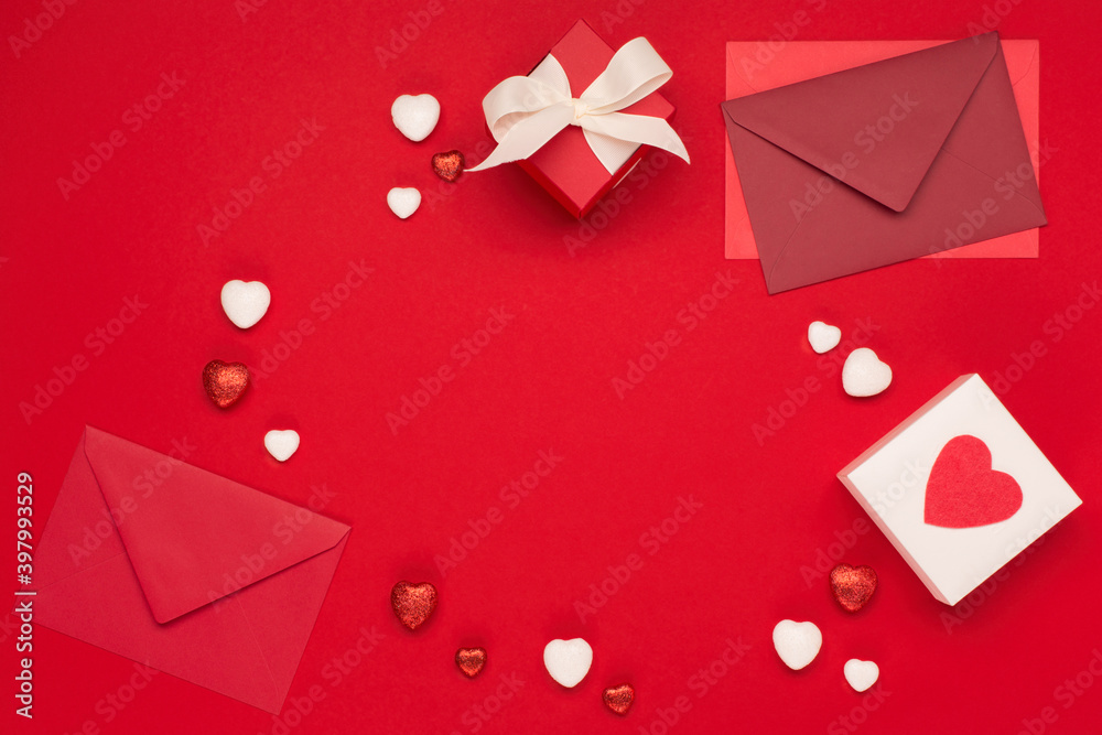 Red white hearts, envelopes and gift box on red background. Valentines day concept. Flat lay, top view, copy space.