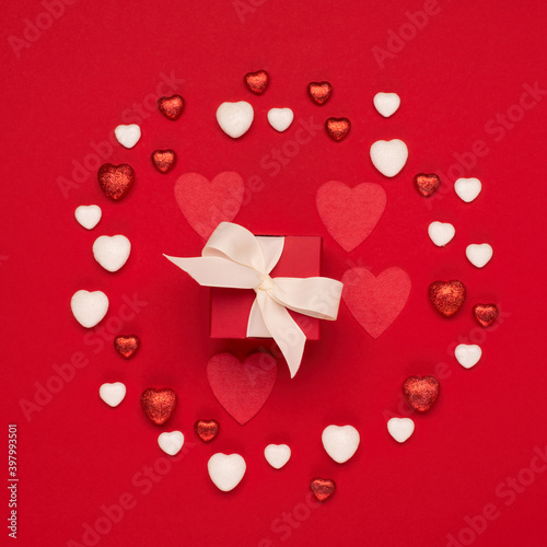 Red white hearts and gift box on red background. Valentines day concept. Flat lay, top view, copy space.