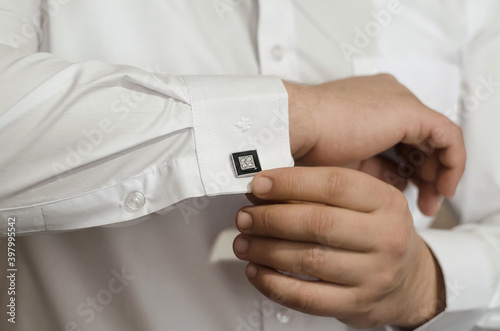 Groom s hands fasten the black cufflinks on his shirt  close-up. The preparations of the groom