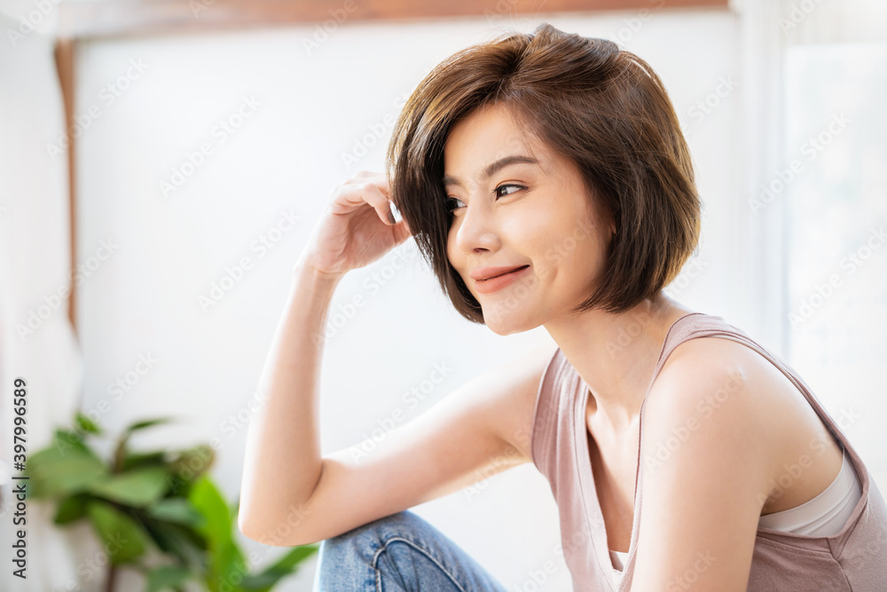 Portrait of beautiful young asian woman with attractive smile hand touching hair in her apartment. Teenage asia girl relax in spring time, asia beauty facial skincare concept