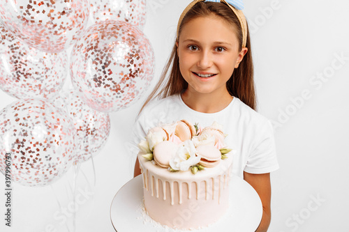 happy little girl holding a beautiful big birthday cake, birthday celebration with balloons, over isolated white background
