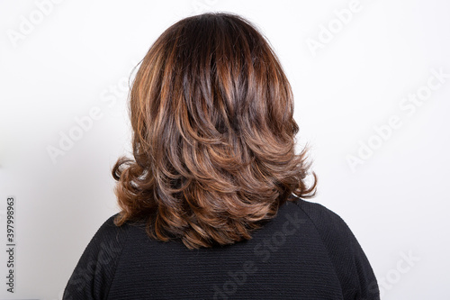 Back view portrait of beautiful dark blonde woman against white background