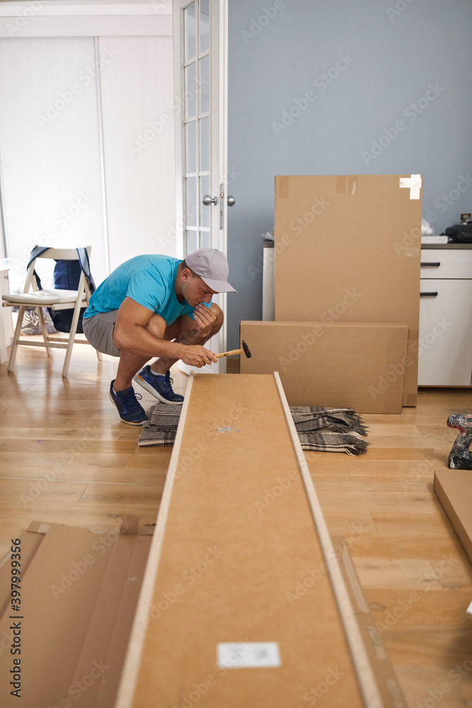 Man assembling furniture in new apartment, moving in and being hardworking. Man assembling furniture in new apartment, moving in and being hardworking.