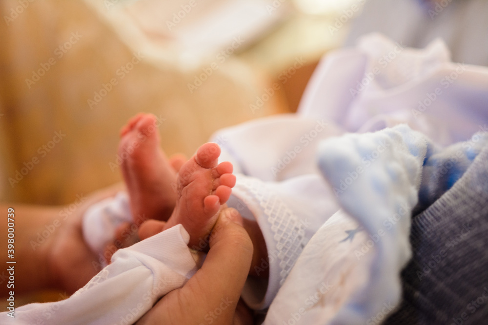 baby baptism, Christian traditions, little legs held by grandmother's hands. baby baptism, Christian traditions, little legs held by grandmother's hands.