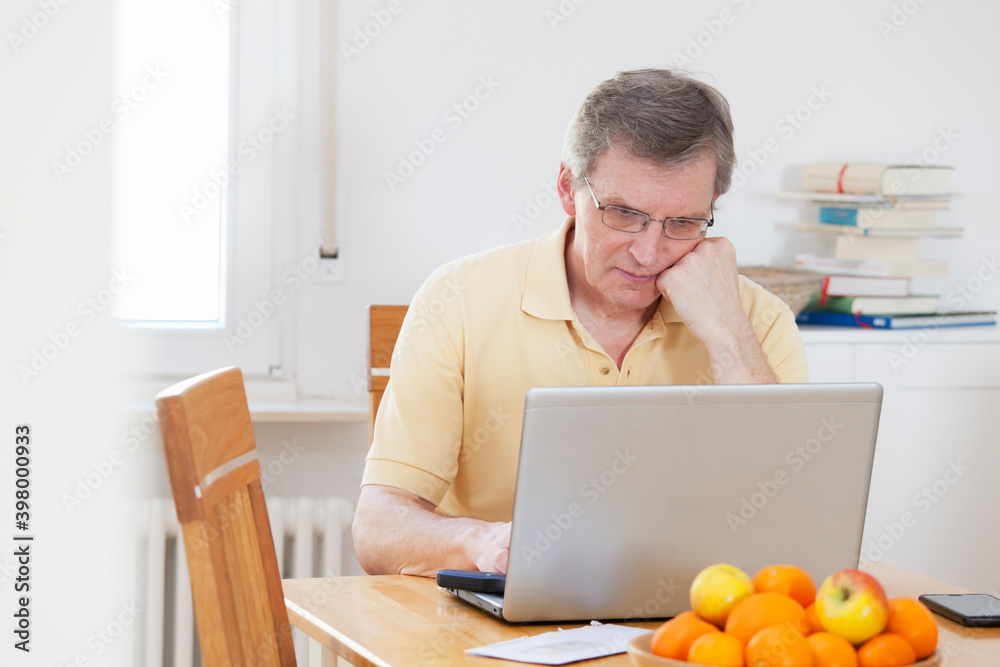 Mature tired man working with computer at home Mature tired man working with computer at home