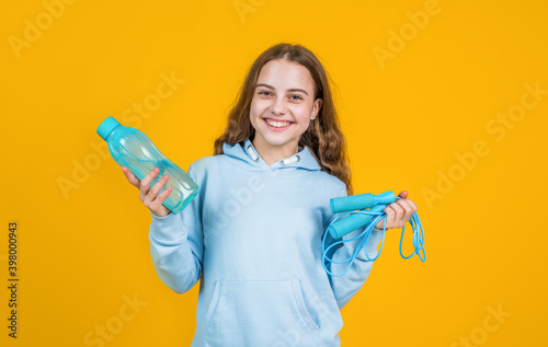 happy smiling teen girl hold sport or fitness equipment of jumping rope and water bottle, hydration