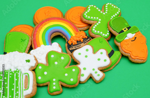 Top view of freshly baked St. Patricks Day decorated sugar cookies on green background. Homemade cookies with shamrock, rainbow, leprechaun with beer and pot of gold decorations. Irish holiday.