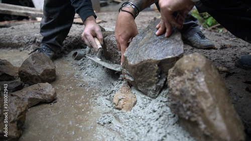 Worker puts rock into fresh concrete photo