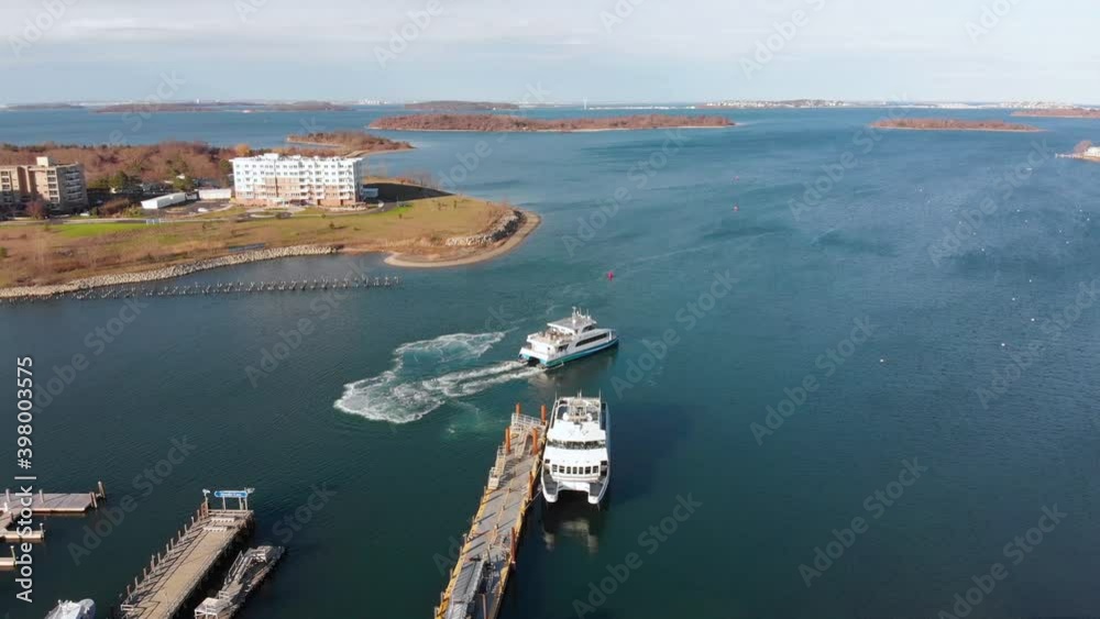 Daytime drone view of a Ferry pulling away from dock in a suburban waterfront community. Daytime drone view of a Ferry pulling away from dock in a suburban waterfront community.