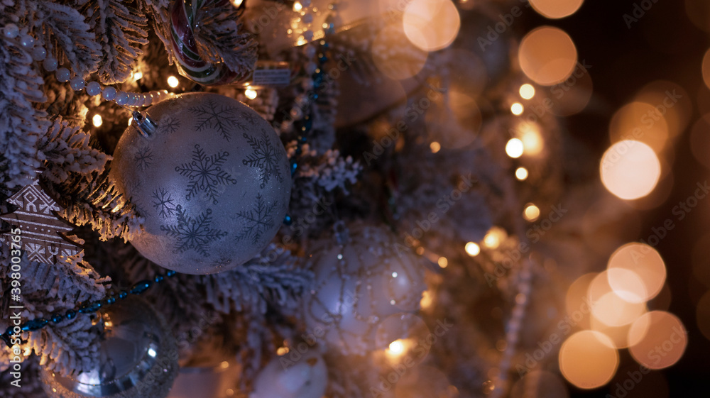 Festive background with a decorated Christmas tree, New Year's toys, holiday lights, neon lights, garland. Dark background with blurred bokeh.