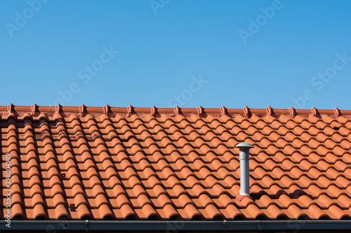 Shingles on rooftop with plastic ventilation pipe in Mediterranean.