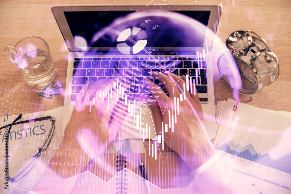Double exposure of man's hands typing over laptop keyboard and forex chart hologram drawing. Top view. Financial markets concept.